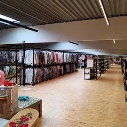 Winkelvloer van kringloopwinkel met rekken vol kleding, stellingen en toonbank