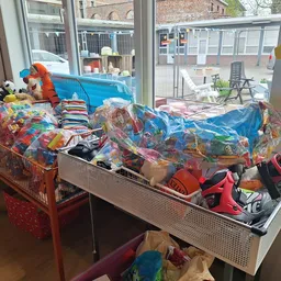 Tafels vol met kinderkleding en speelgoed in plastic verpakkingen in een kringloopwinkel