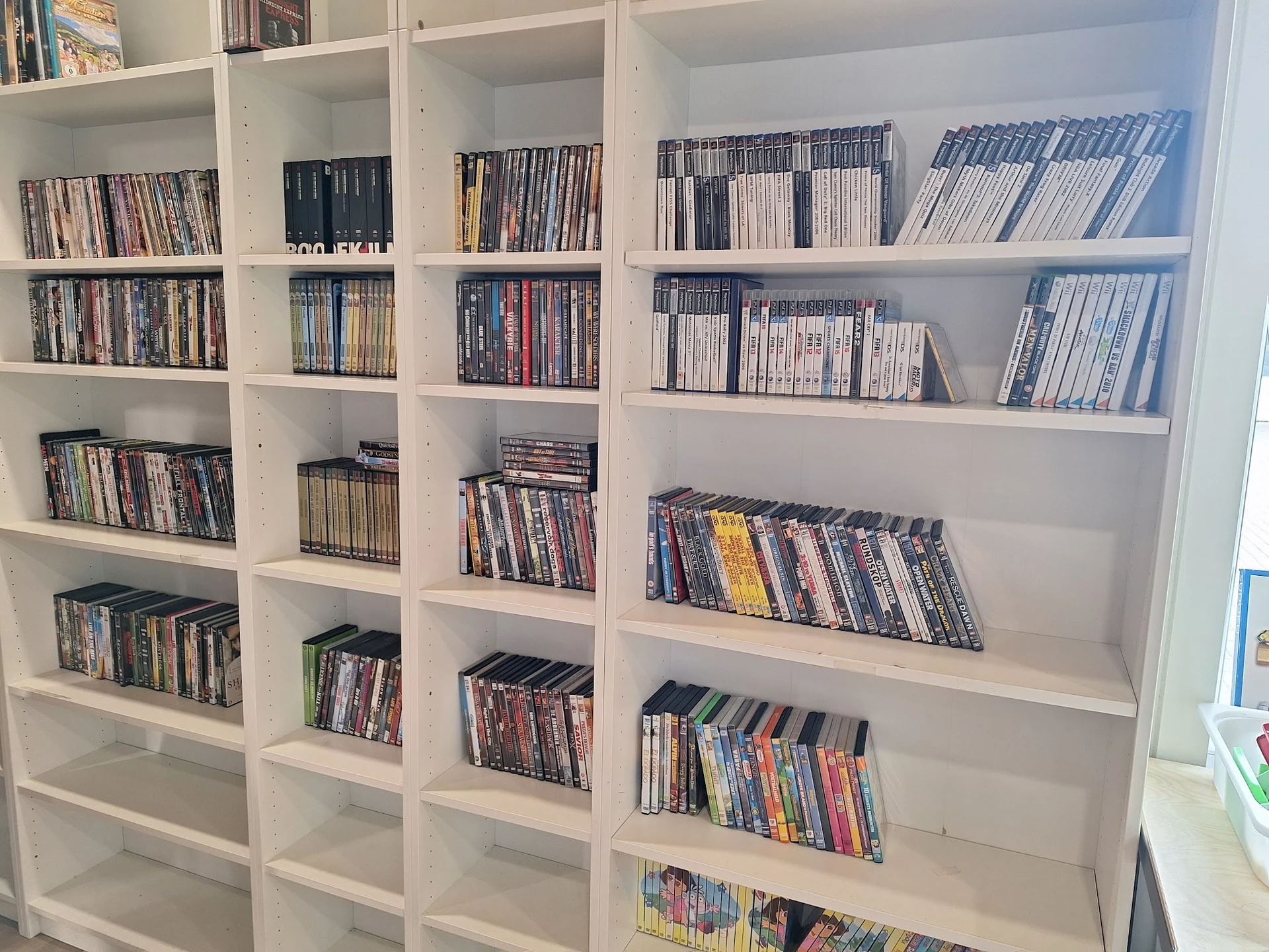 Witte stellingen volgestapeld met dvd's en blu-rays in hun doosjes, netjes georganiseerd per plank