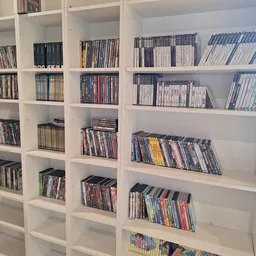 Witte stellingen volgestapeld met dvd's en blu-rays in hun doosjes, netjes georganiseerd per plank