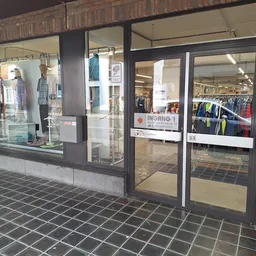 Winkelgevel met glazen deuren en ramen, kleding zichtbaar in etalage