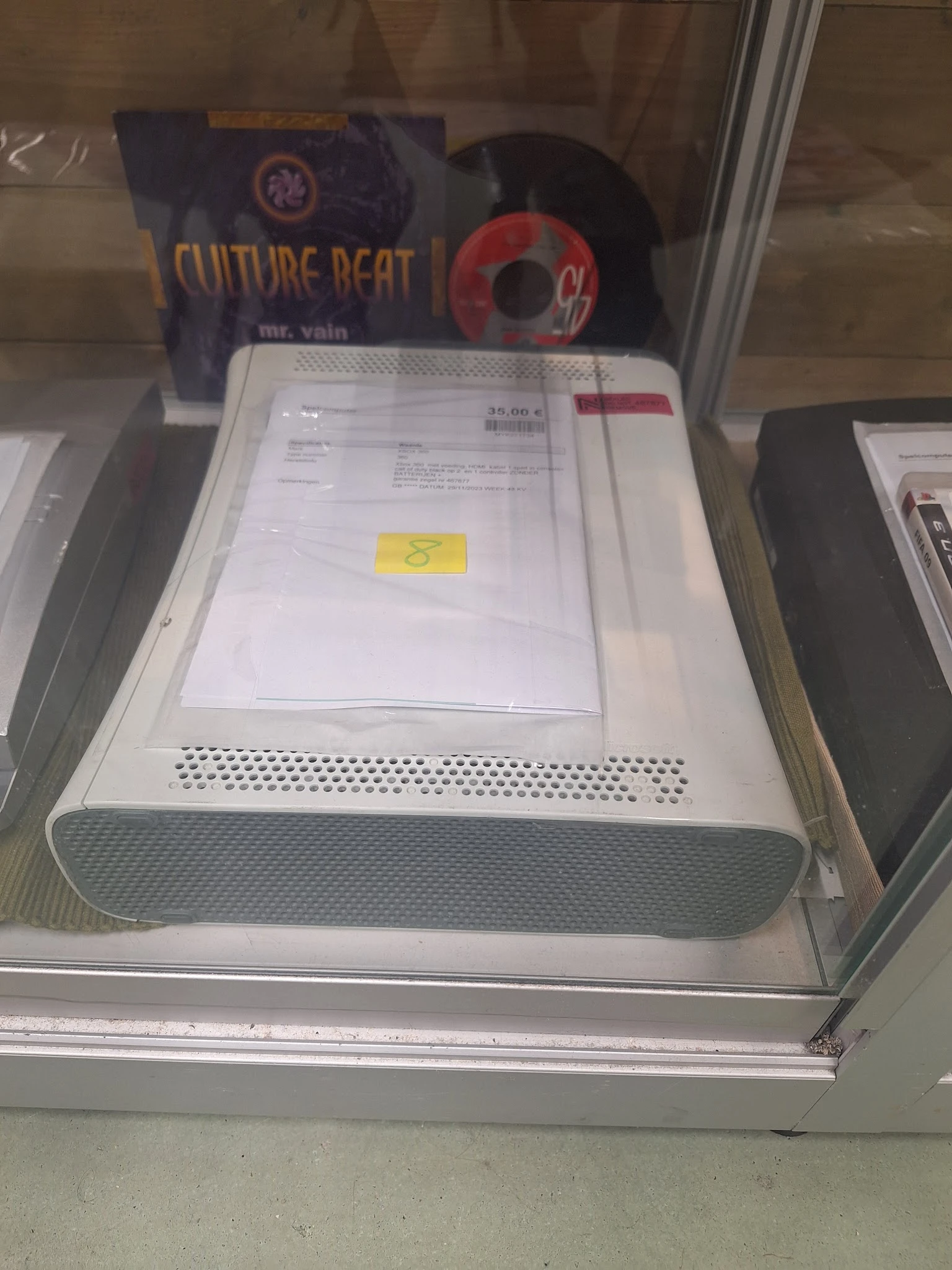 Witte apparaat met ventilatierooster en documenten op het deksel in een kunststof verpakking