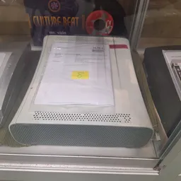 Witte apparaat met ventilatierooster en documenten op het deksel in een kunststof verpakking