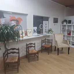 Winkelbinnenruimte met houten stoelen, planten, wit rek met decoratie en artwork aan muur