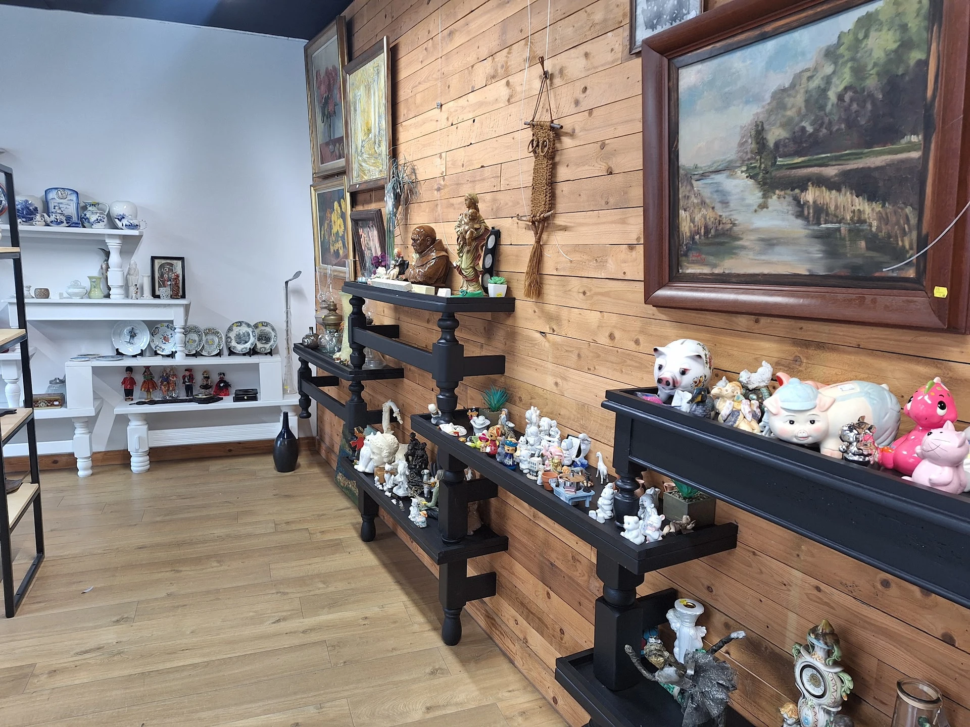 Winkelinterieur met houten wanden, zwarte stellingen vol decoratieve items, schilderijen en witte boekenkasten op de achtergr