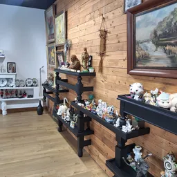 Winkelinterieur met houten wanden, zwarte stellingen vol decoratieve items, schilderijen en witte boekenkasten op de achtergr