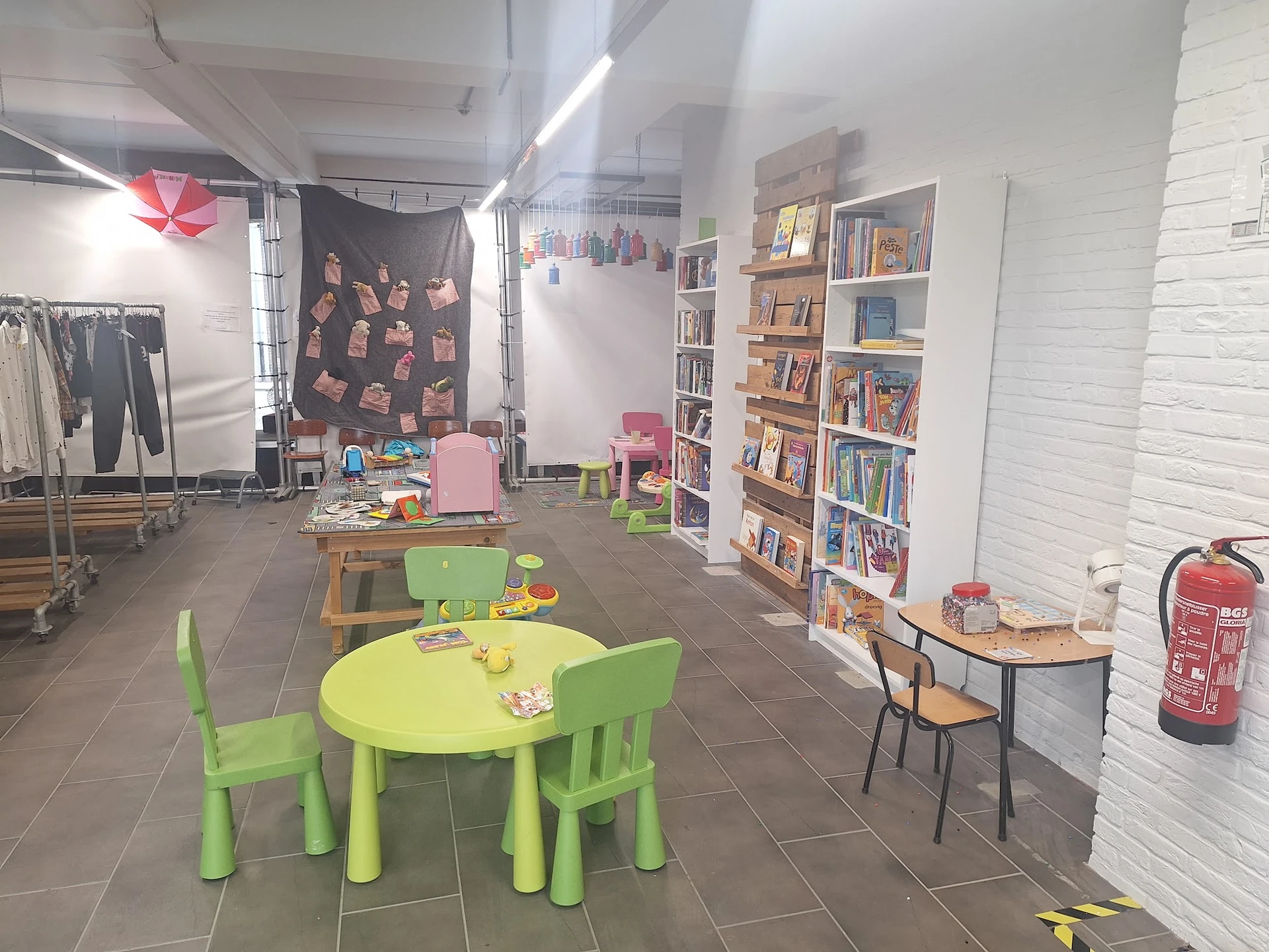 Winkelvloer met groen kindertafeltje, boekenkasten, kledingrek en speelhoek