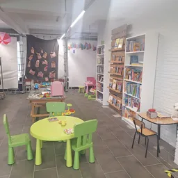 Winkelvloer met groen kindertafeltje, boekenkasten, kledingrek en speelhoek