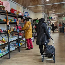 Winkelinterieur met speelgoed en boeken in stellingen, klanten winkelen, houten vloer