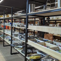 Glazen vitrinekasten met servies, borden, kopjes en ander huishoudelijk aardewerk op elkaar gestapeld