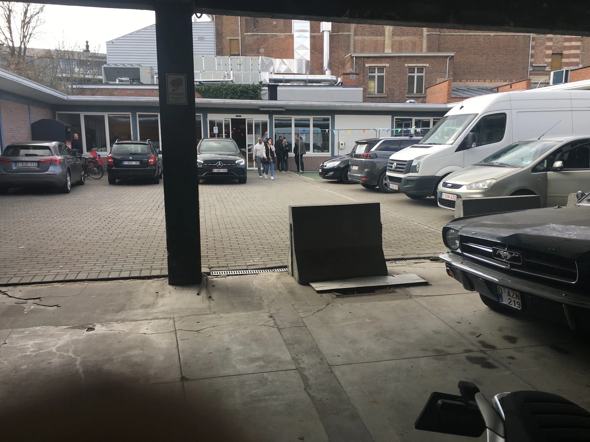 Parkeerplaats met auto's voor een winkel, gezien vanaf binnenuit achter glas