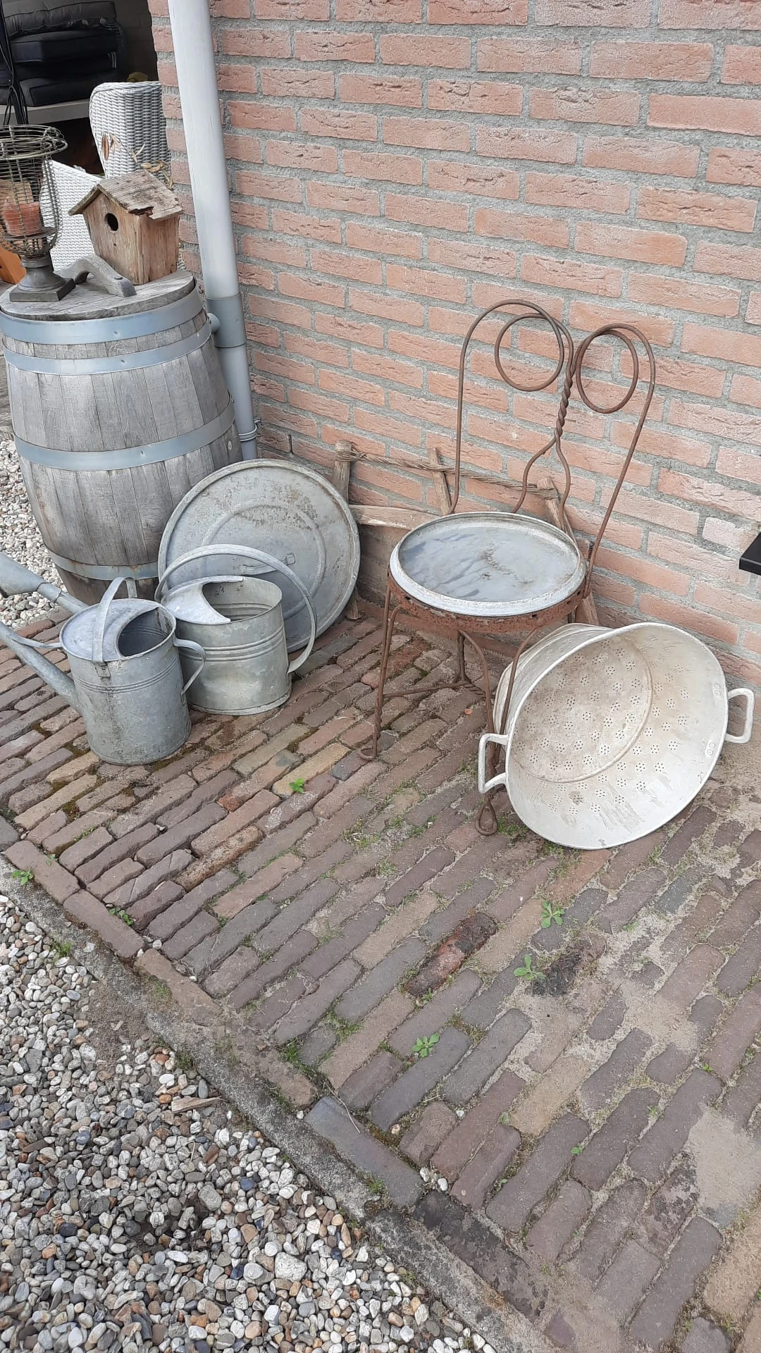 Verzameling gebruikte metalen huishoudartikelen op een bakstenen terras