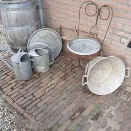 Verzameling gebruikte metalen huishoudartikelen op een bakstenen terras