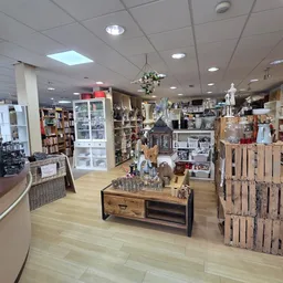 Overzicht van de winkelvloer met rekken, vitrines, houten toonbank en uitgestalde merchandise in een kringloopwinkel