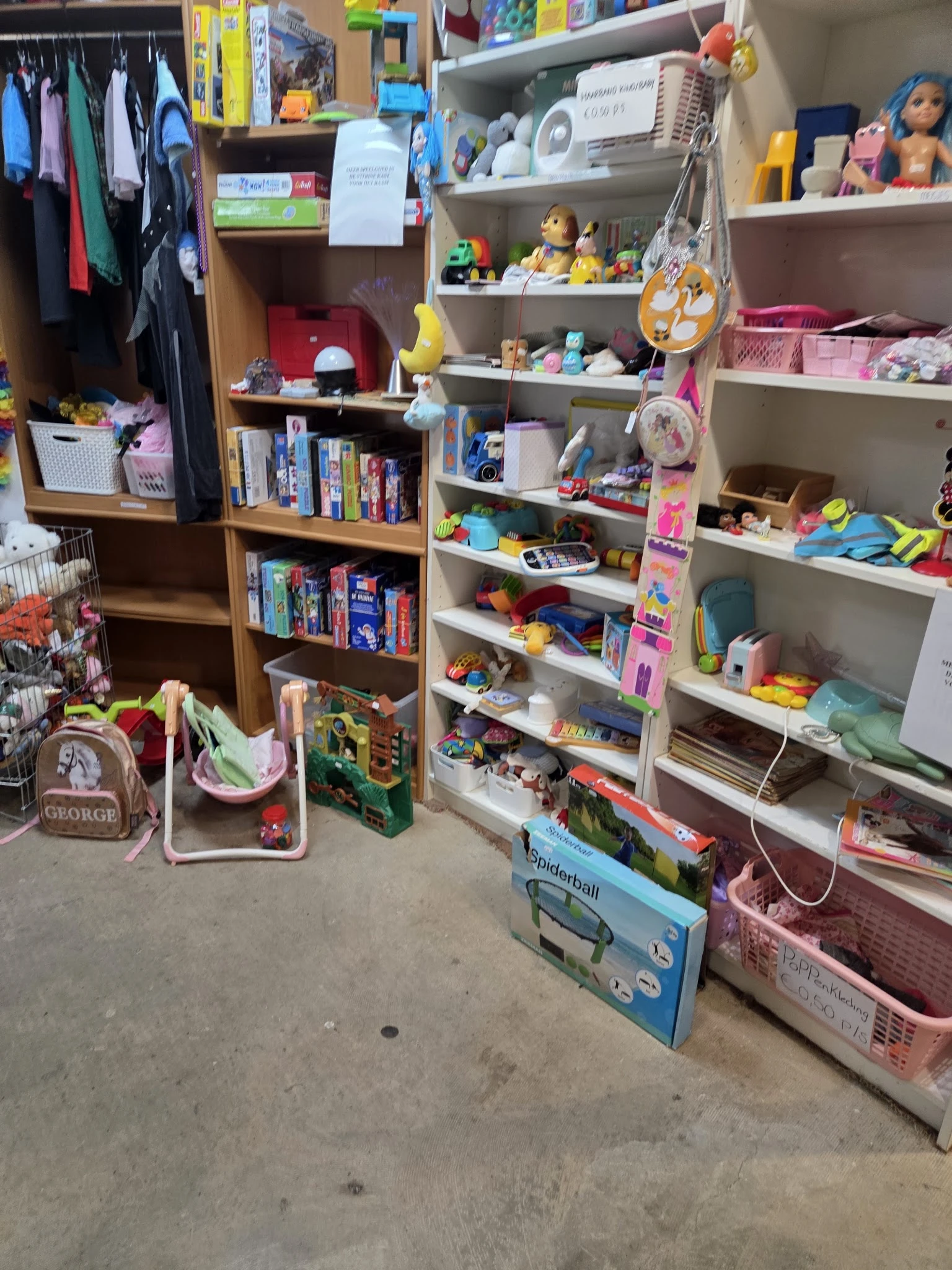 Winkelinterieur met houten en witte kasten vol speelgoed, boeken en diverse huishoudartikelen
