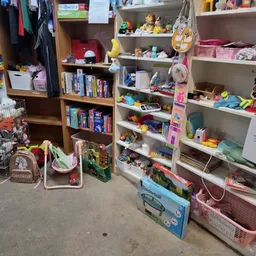 Winkelinterieur met houten en witte kasten vol speelgoed, boeken en diverse huishoudartikelen