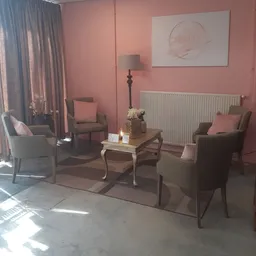Ingerichte woonkamer met roze wanden, meubels en accessoires in een kringloopwinkel