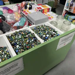 Groene boxen met grote hoeveelheden gekleurde kralen en aan de zijkanten gestapelde wol en andere materialen