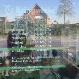 Openingstijden en contactgegevens van een winkel op een raam weergegeven