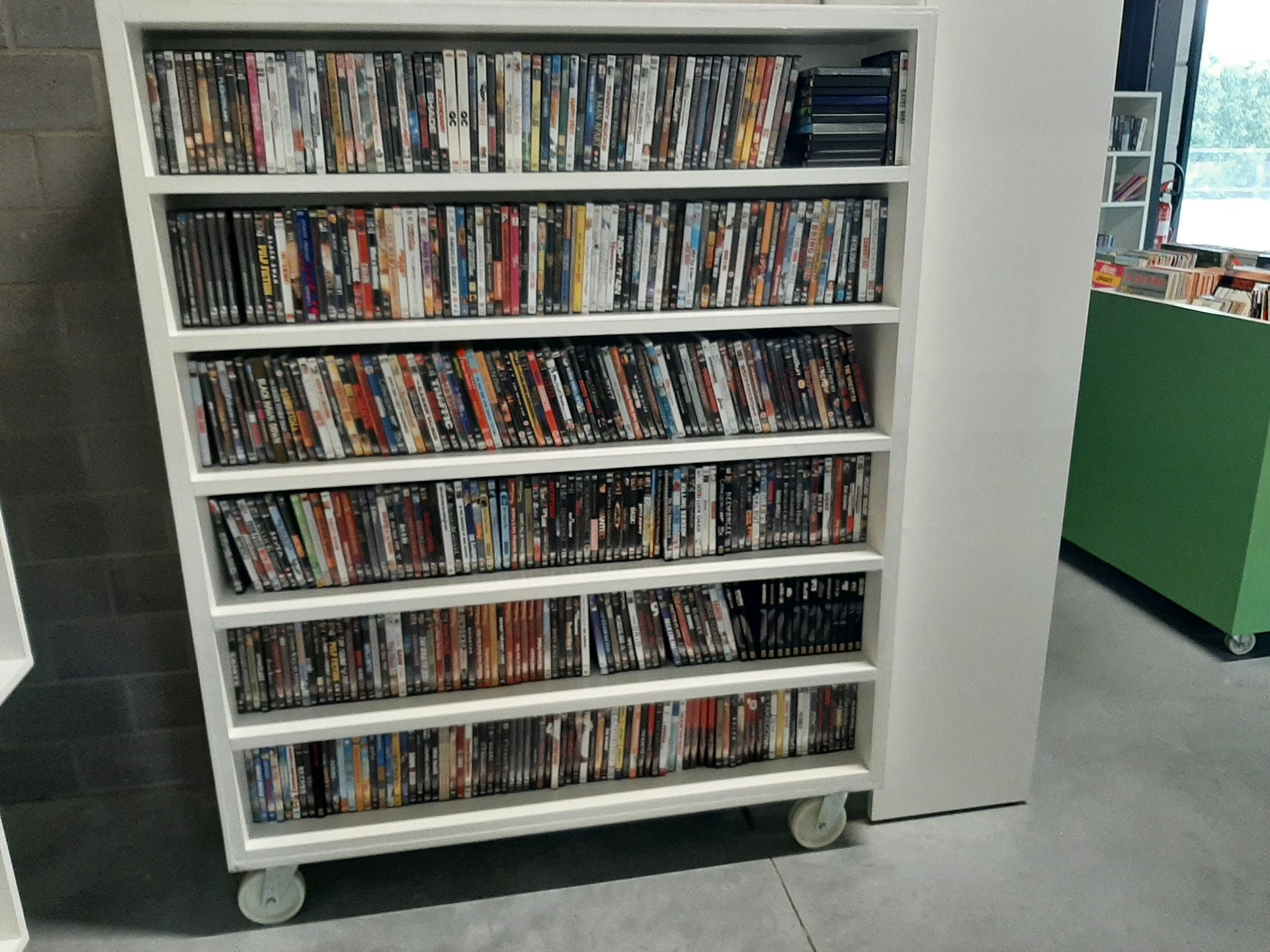 Witte boekenkast met zes schappen vol dvd's en blu-rays op wieltjes