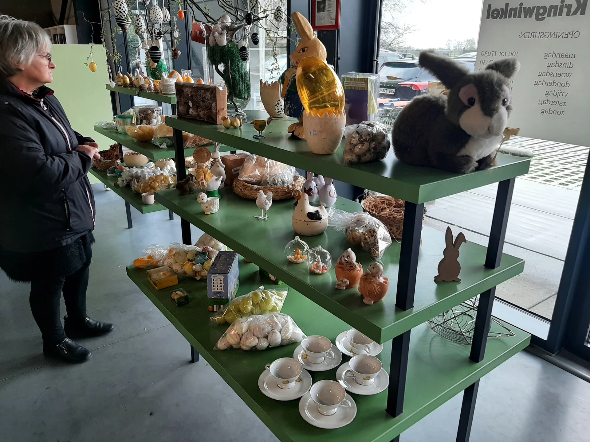Groene display-tafels met diverse gebruiksartikelen en decoratieve items zoals servies, houten beeldjes en potten
