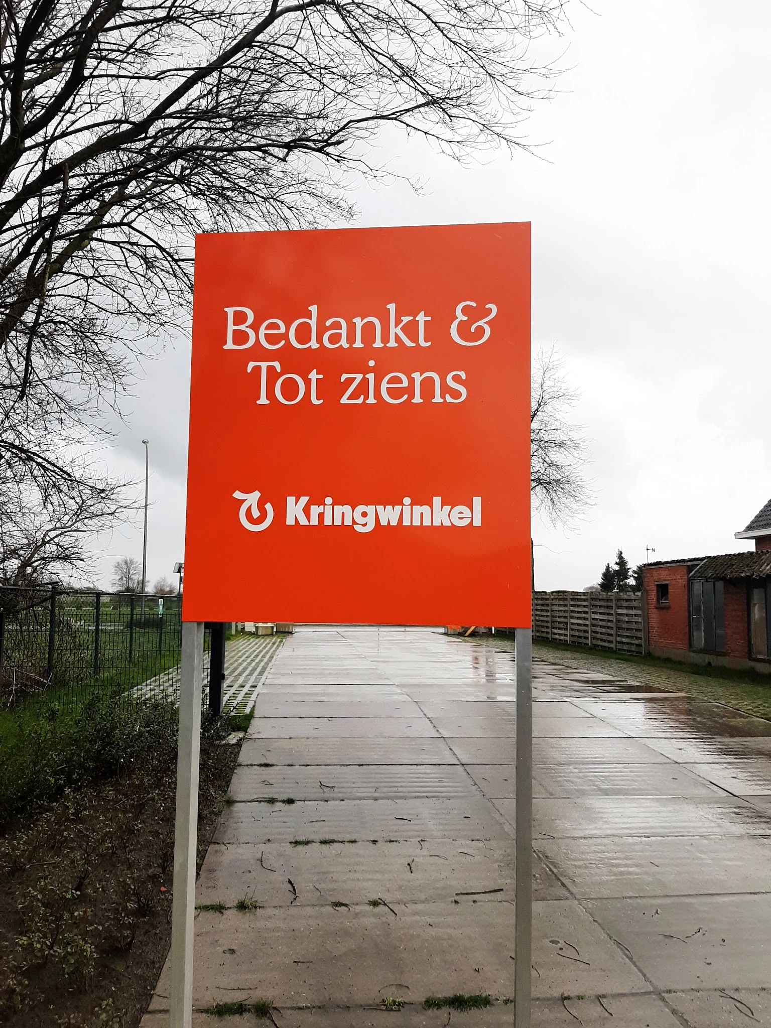 Rood welkomstbord met 'Bedankt & Tot ziens' en Kringwinkel-logo bij de ingang van de winkel