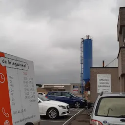 Parkeerterrein met auto's en bedrijfsgebouwen onder bewolkte lucht
