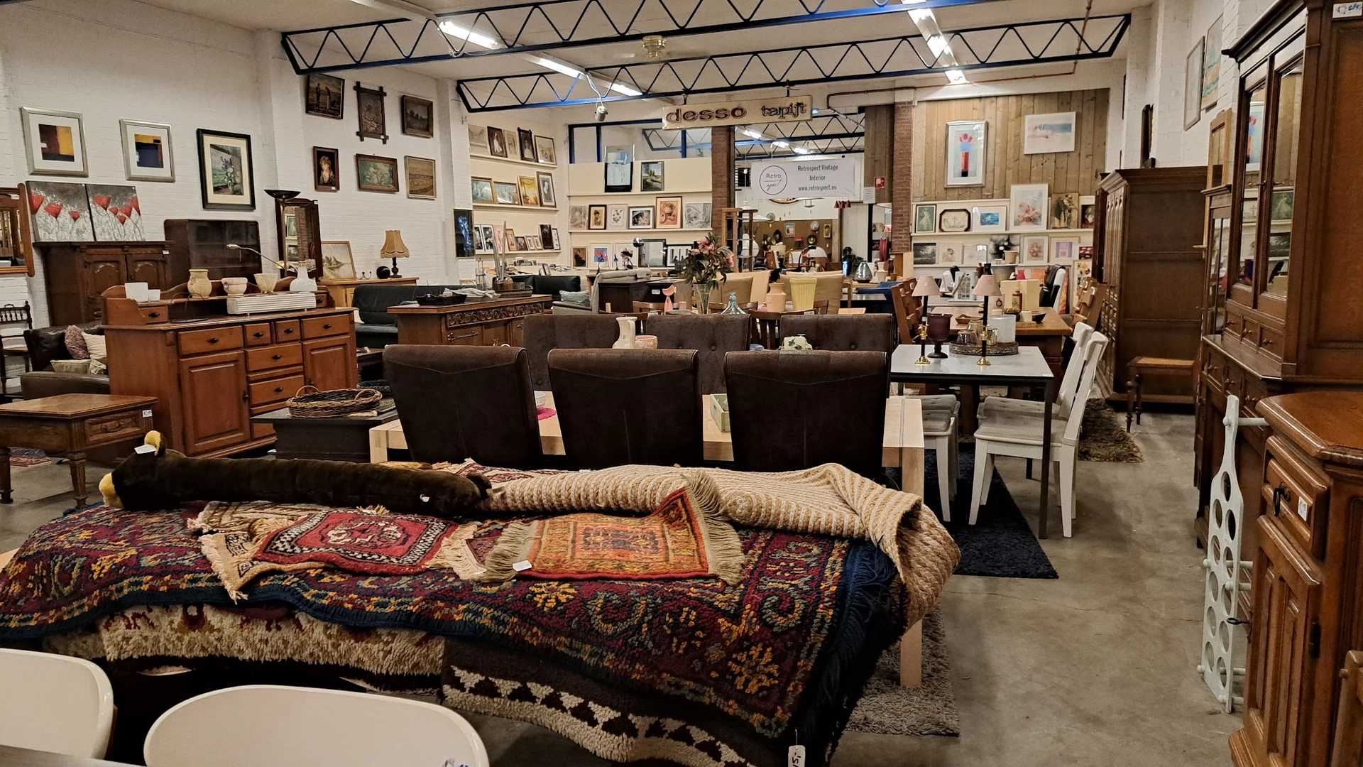 Winkelvloer met bruine stoelen, uitgestalde meubels, kunst aan muren en diverse spullen op rekken