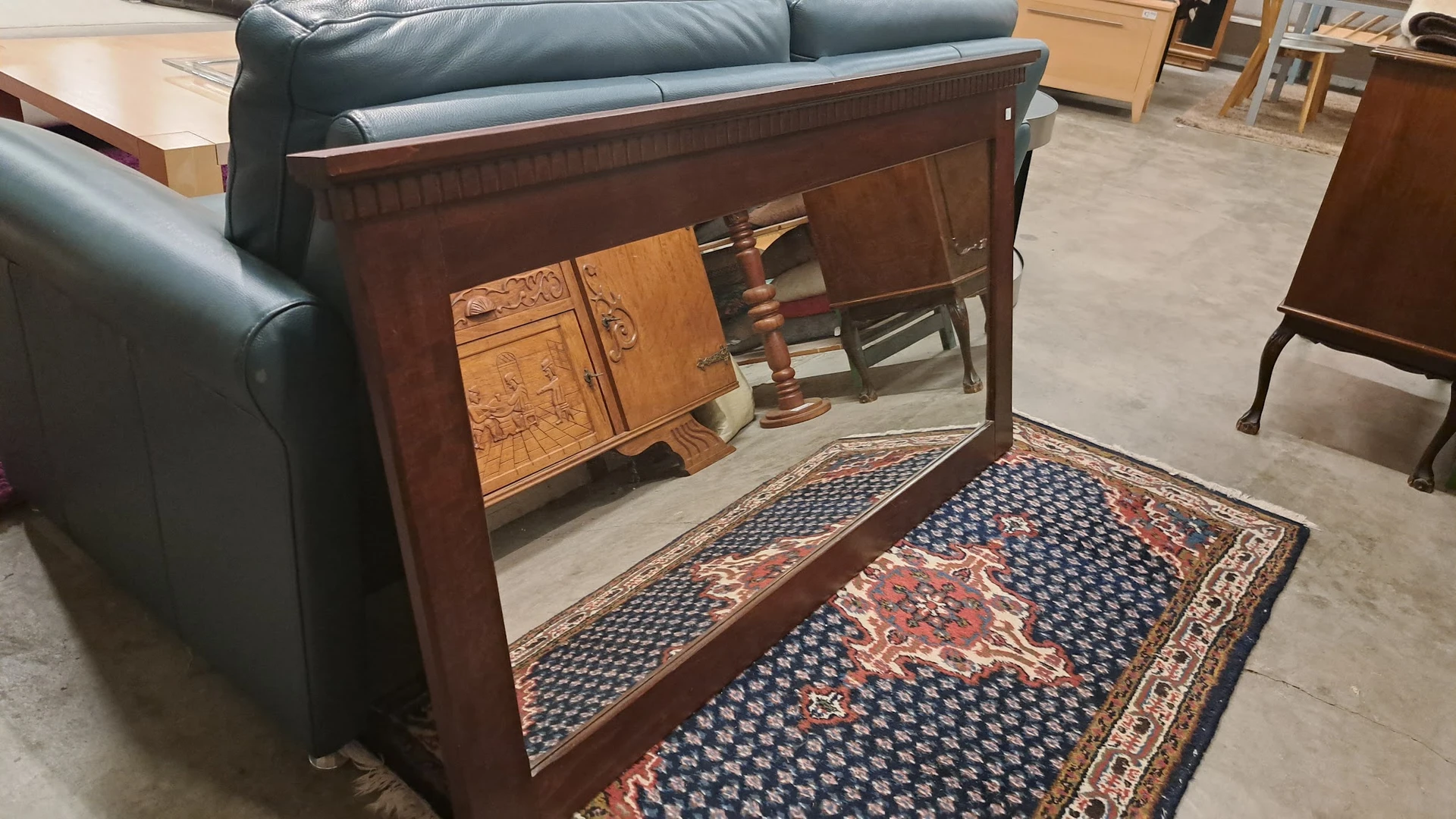 Houten antieke vitrinekast met spiegeldeuren, op een oosters tapijt in de winkel