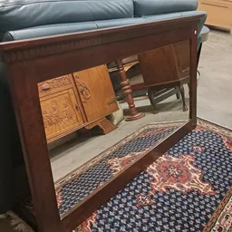 Houten antieke vitrinekast met spiegeldeuren, op een oosters tapijt in de winkel