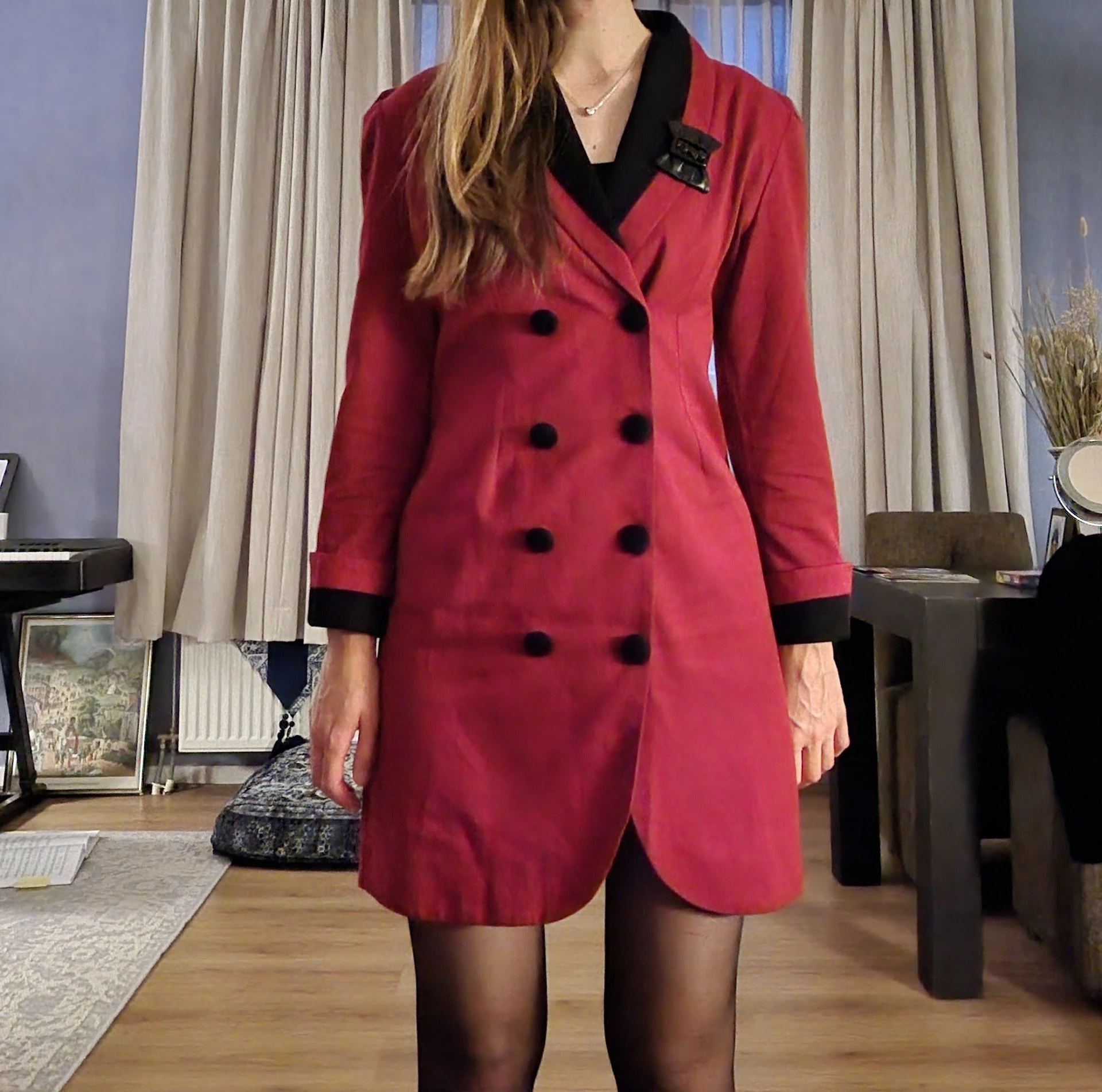 Rode blazer-jurk met zwarte knopen en manchetten, op een etalagepop in de winkel