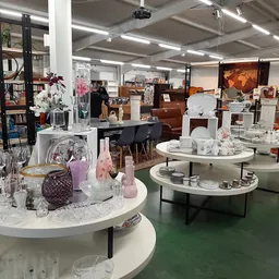 Winkelvloer met ronde witte toonbanken met huishoudelijke spullen, meubels en decoratie op de achtergrond