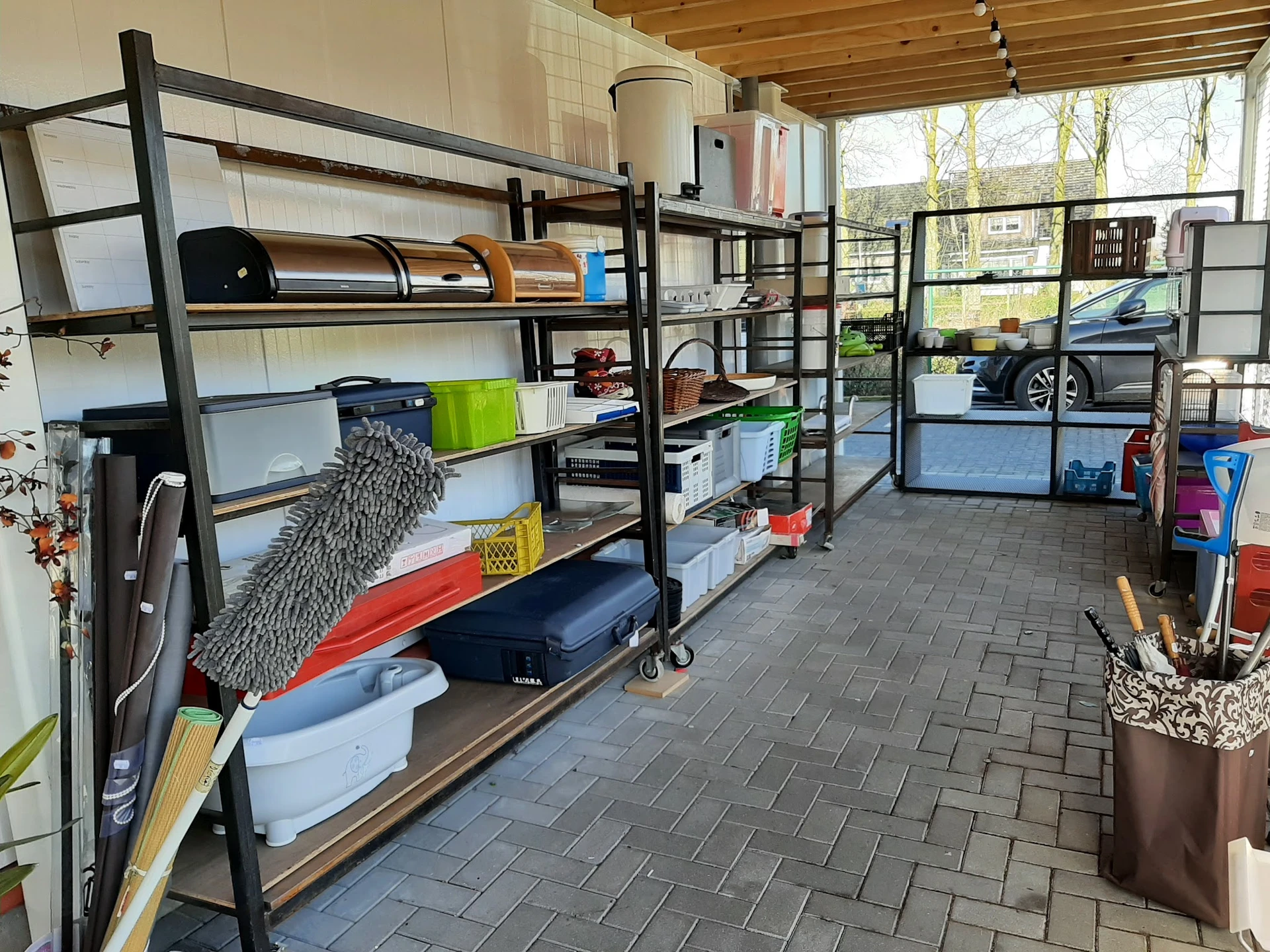 Stellingen met opgeslagen spullen in een kringloopwinkel, onder meer kusses, dozen en huishoudartikelen