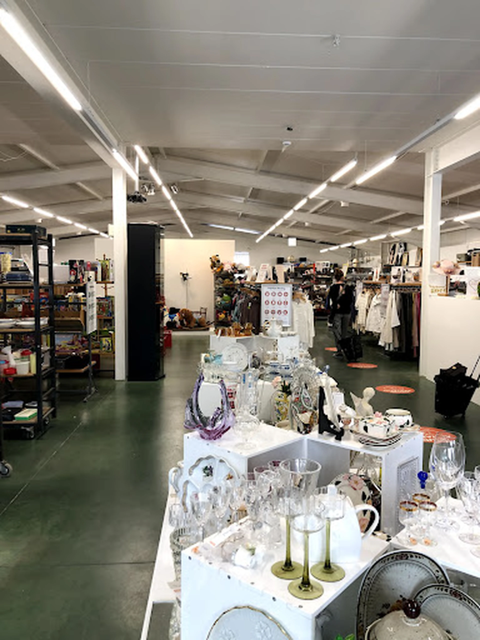 Winkelinterieur met displays, kleding aan rekken en verschillende soorten tweedehandsartikelen uitgestald