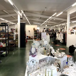 Winkelinterieur met displays, kleding aan rekken en verschillende soorten tweedehandsartikelen uitgestald