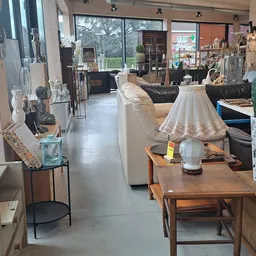 Winkelvloer van kringloopwinkel met meubels, decoraties en diverse spullen langs de zijkanten