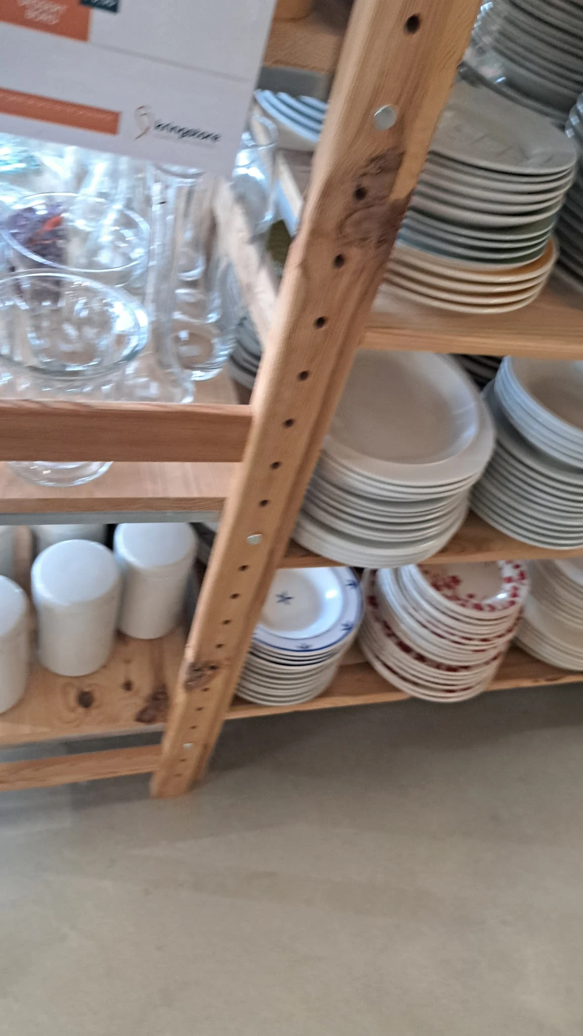 Houten stellingen met serviesgoed: gestapelde borden, kopjes en glazen