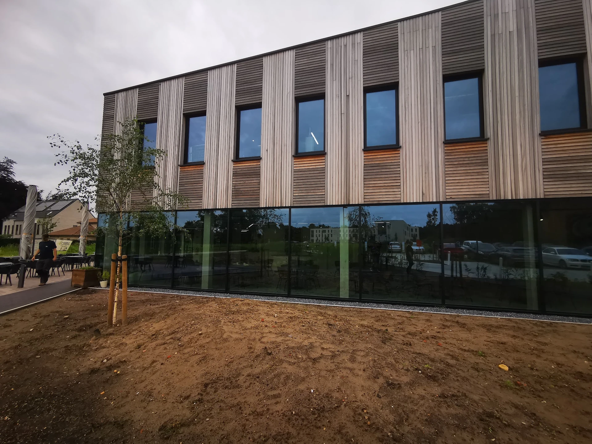 Moderne gevel van een gebouw met verticale houten en metalen strips, grote ramen en glazen beglazing op begane grond