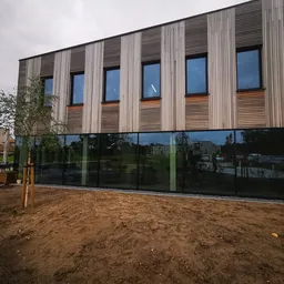 Moderne gevel van een gebouw met verticale houten en metalen strips, grote ramen en glazen beglazing op begane grond