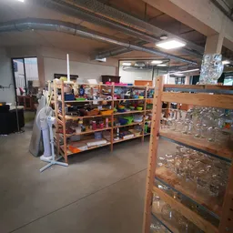 Winkelvloer met houten stellingen gevuld met gekleurde dozen en voorwerpen, zichtbaar aanbod van spullen