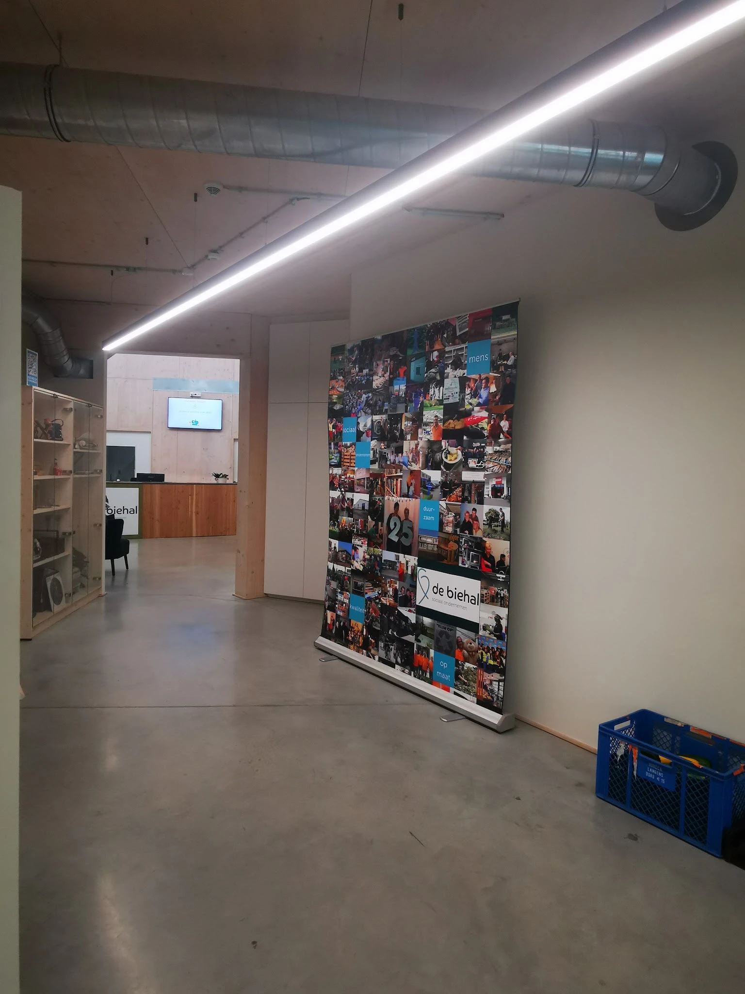 Winkelinterieur met betonnen vloer, witte wanden, lineaire plafondverlichting en een grote collage van foto's aan de muur