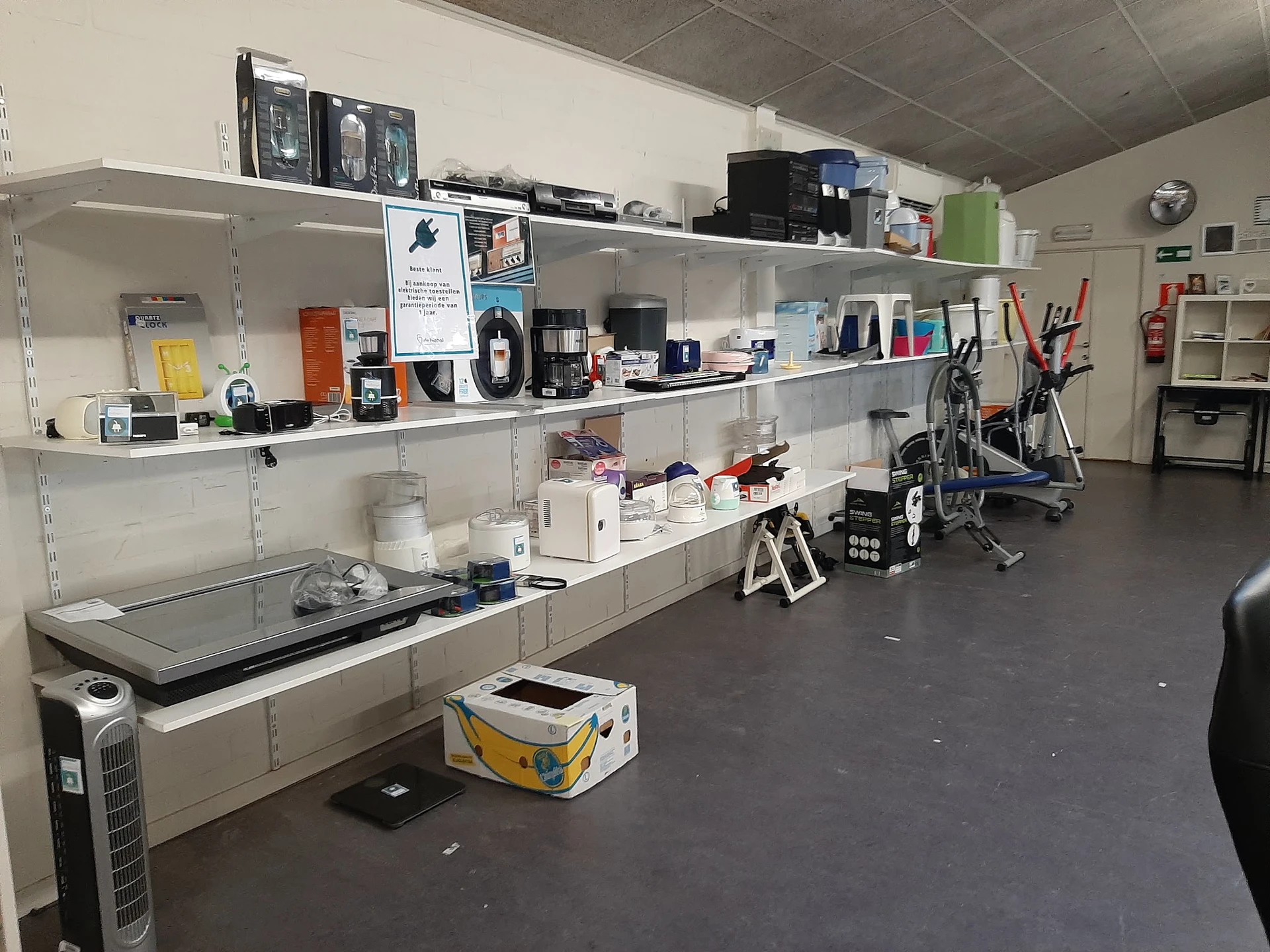 Stellingen met elektronische apparaten, printers, computers en diverse huishoudelijke artikelen