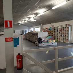 Winkelvloer met stellingen vol spullen, glazen afdeling en rood brandblusapparaat
