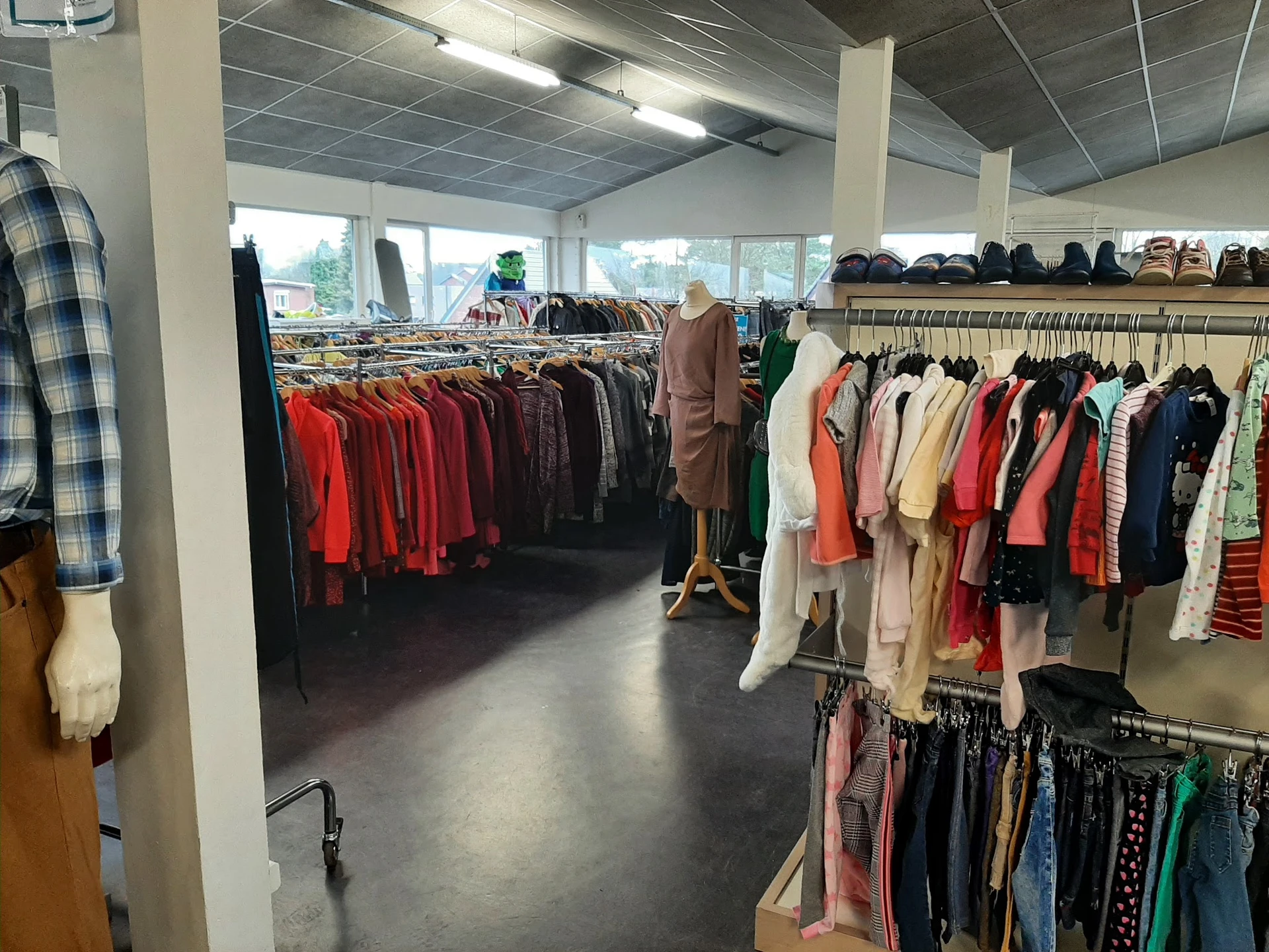 Winkelinterieur met rekken vol tweedehands kleding in verschillende kleuren en stijlen