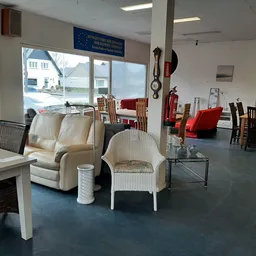 Winkelvloer met tweedehandsmeubels: fauteuils, stoelen, tafels en diverse huishoudartikelen uitgestald onder fluorescente ver