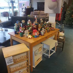 Houten tafel met diverse decoratieve beeldjes, poppen en huishoudelijke artikelen uitgestald
