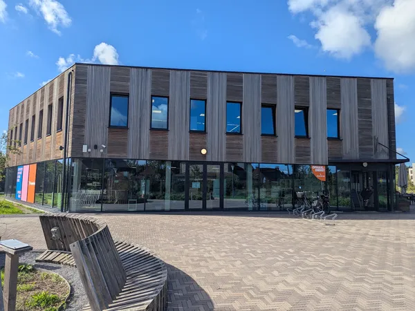 Moderne gevel van kringloopwinkel met donkergroene houten bekleding, grote ramen op begane grond en eerste verdieping, vlakke