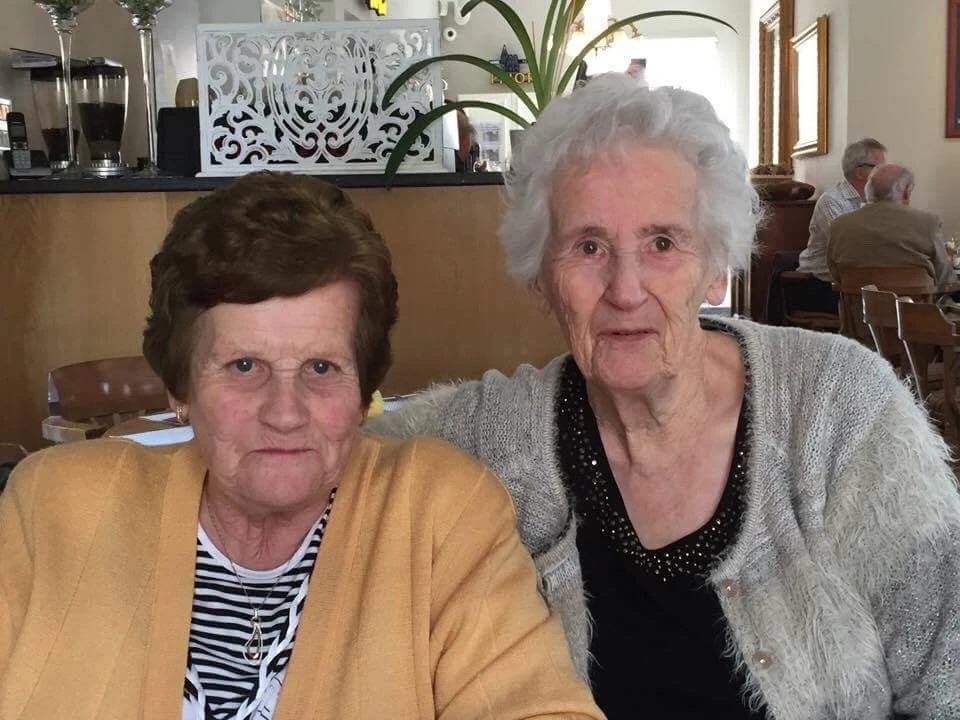 Twee vrouwen poseren samen voor de camera in een winkelinterieur