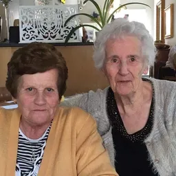 Twee vrouwen poseren samen voor de camera in een winkelinterieur