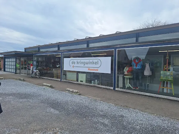 Voorgevel van kringloopwinkel met ramen, uitgestalde spullen en fietsen ernaast